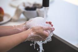 Eine Person wäscht ihre Hände mit Seife unter fließendem Wasser.