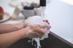 Eine Person wäscht ihre Hände mit Seife unter fließendem Wasser.